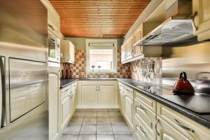 Table with chairs and flowers located near lounge area and kitchen in spacious room of contemporary apartment