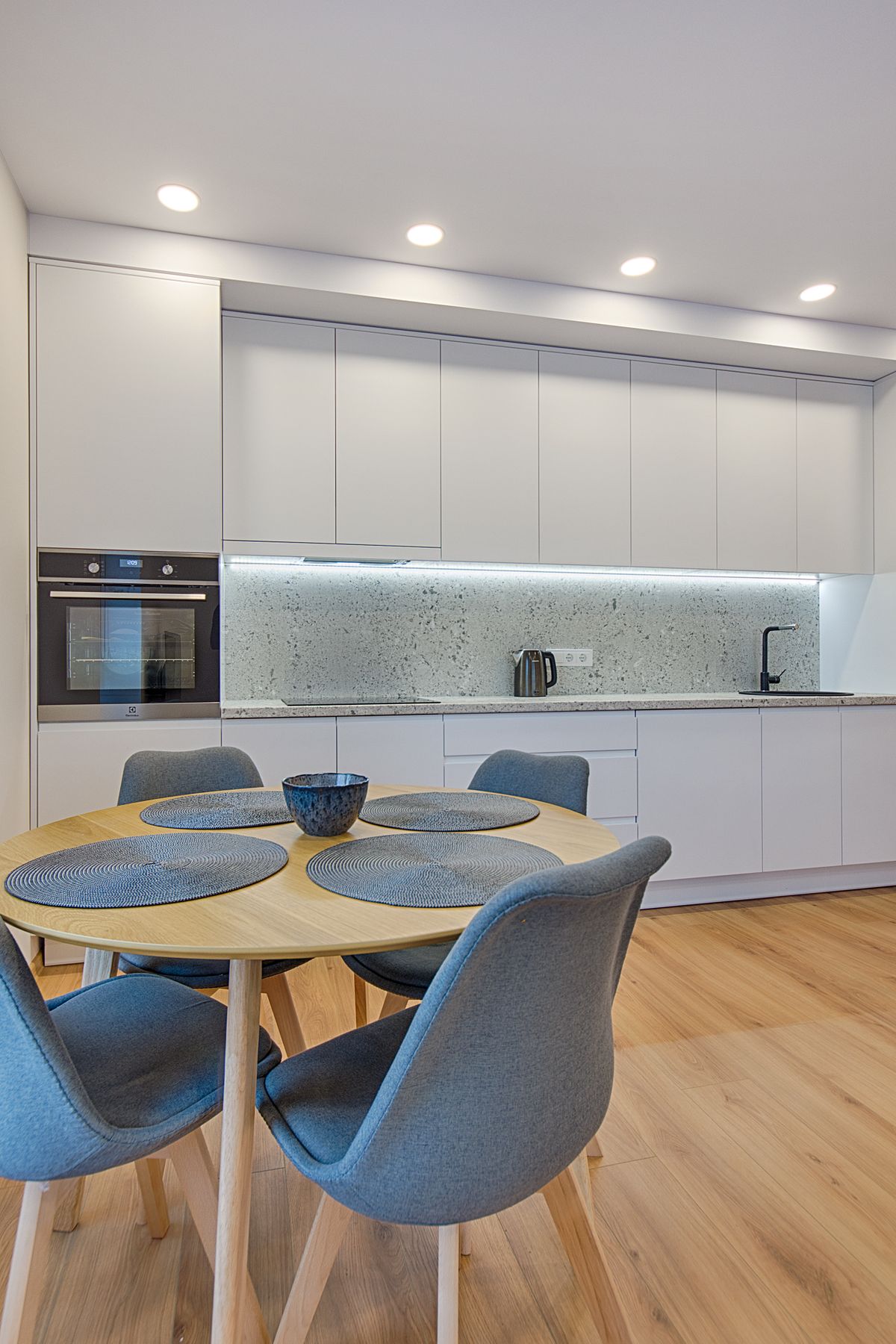 White minimalist kitchen with a round oak table