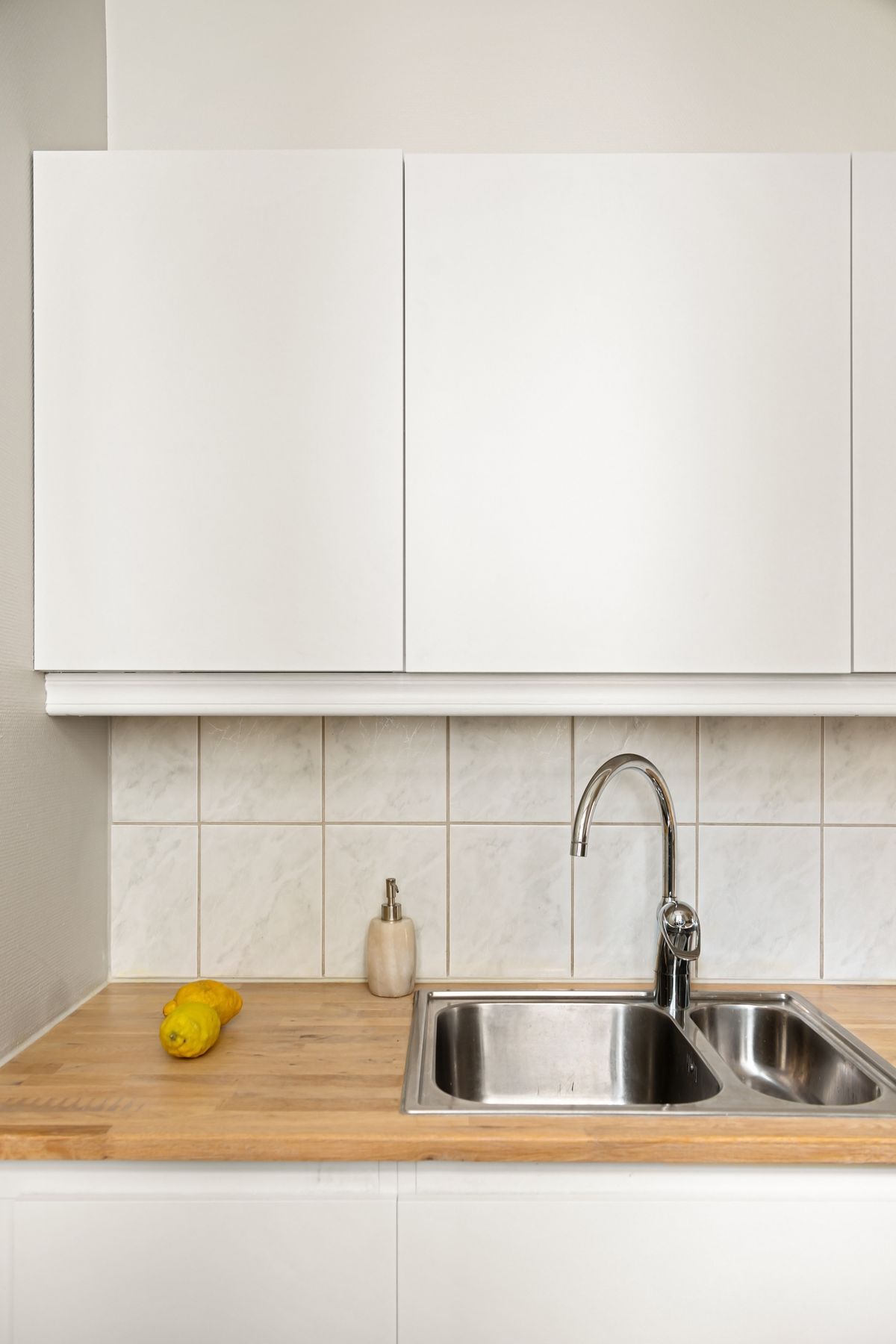 White wall cabinets above a solid oak worktop and sink