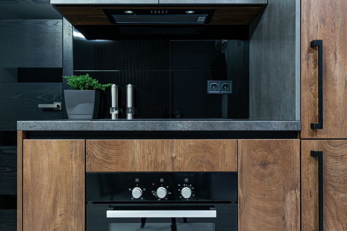 Dark timber kitchen with a stone worktop and integrated oven