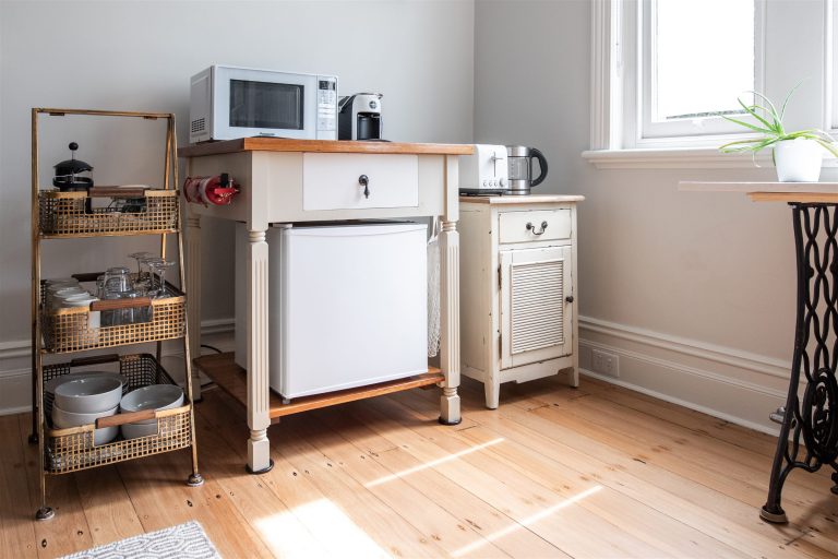 Compact temporary kitchen setup with a small refrigerator, microwave and kettle