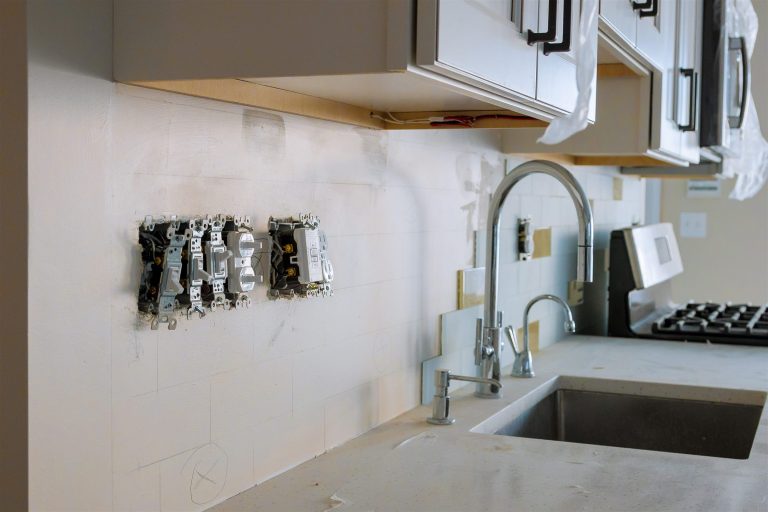Open GFCI outlet and switch boxes on a kitchen backsplash wall during a remodel