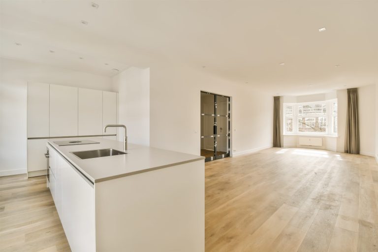 Kitchen island with a sink beside a wide, clear walkway on a light wood floor