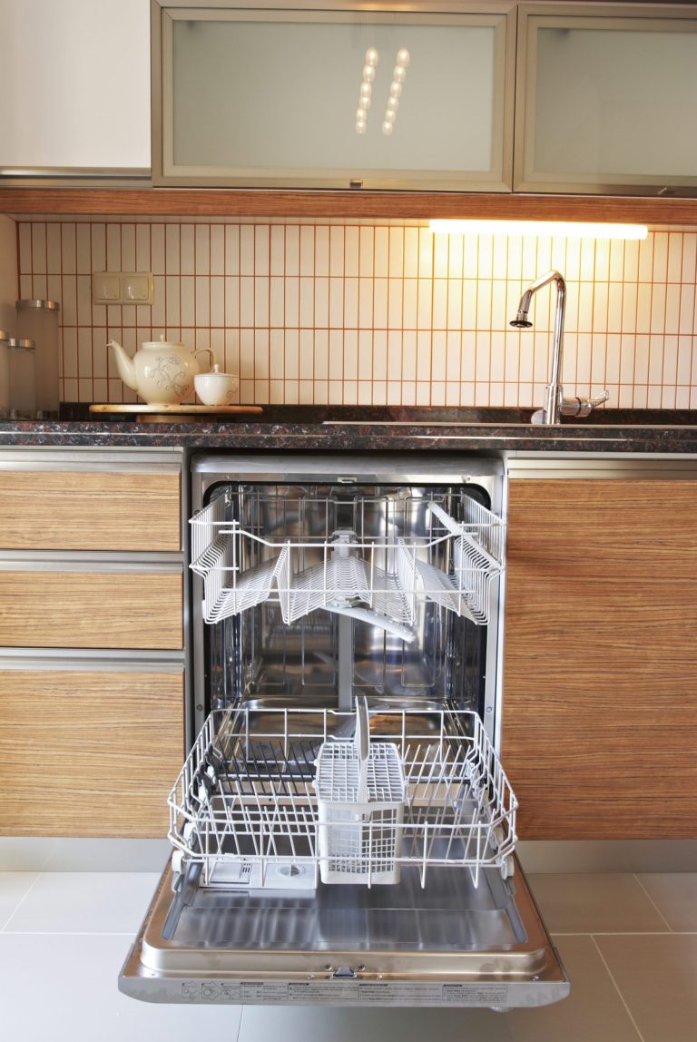 Open dishwasher with empty racks pulled out in a kitchen with wood cabinets